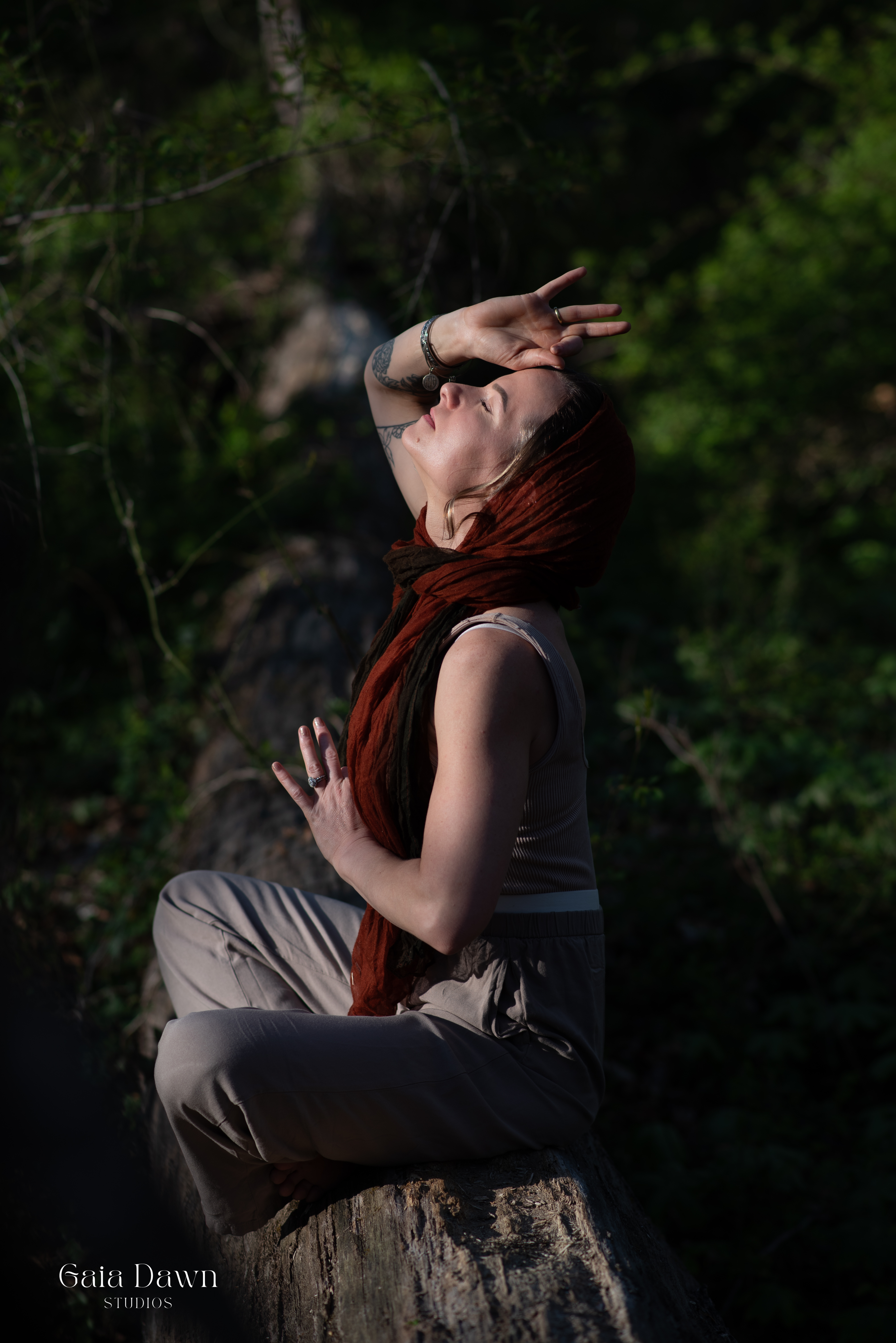 Briana in meditation, draped in a red scarf, bathed in golden light